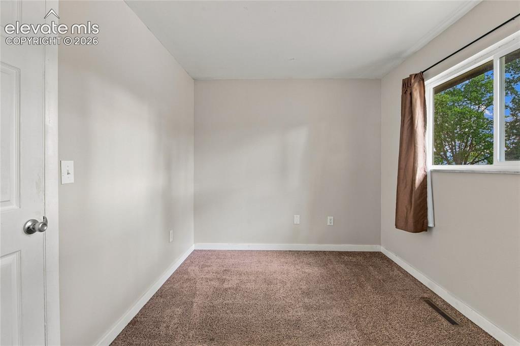 Image 18 of 34: Main level bedroom with large window, carpet and closet space