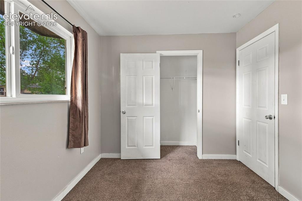 Image 19 of 34: Main level bedroom with large window, carpet and closet space