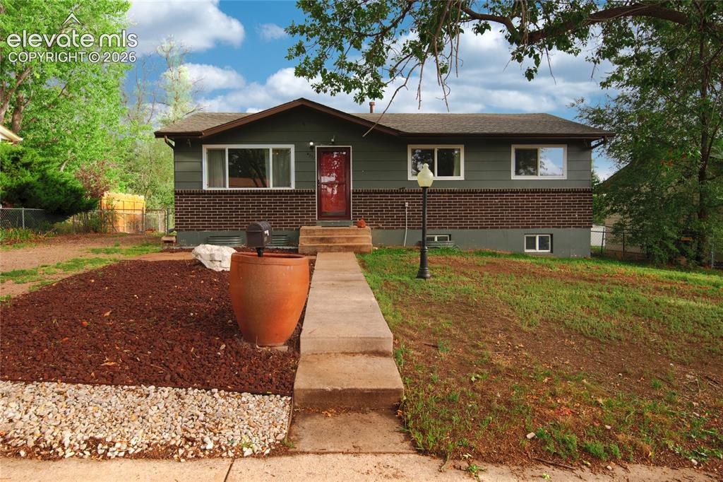 Image 2 of 34: Welcoming brick ranch home featuring a concrete walkway, mature landscaping