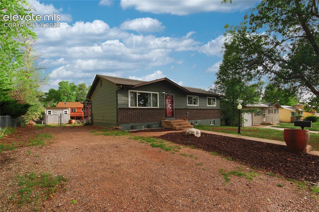 Image 3 of 34: Welcoming brick ranch home featuring a concrete walkway, mature landscaping
