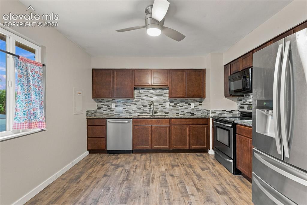 Image 8 of 34: Kitchen featuring wood-finish flooring, dark wood cabinetry, stainless stee