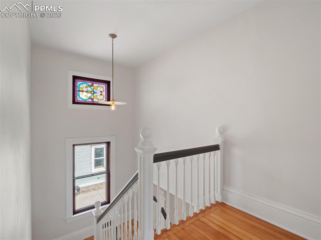 Image 10 of 41: The grand staircase if full of light with a stained glass window and a vint