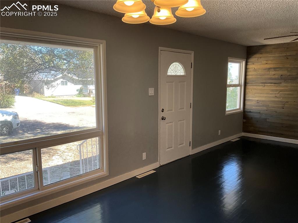 Image 11 of 43: Entrance foyer featuring dark wood-type flooring, wooden walls, a chandelie