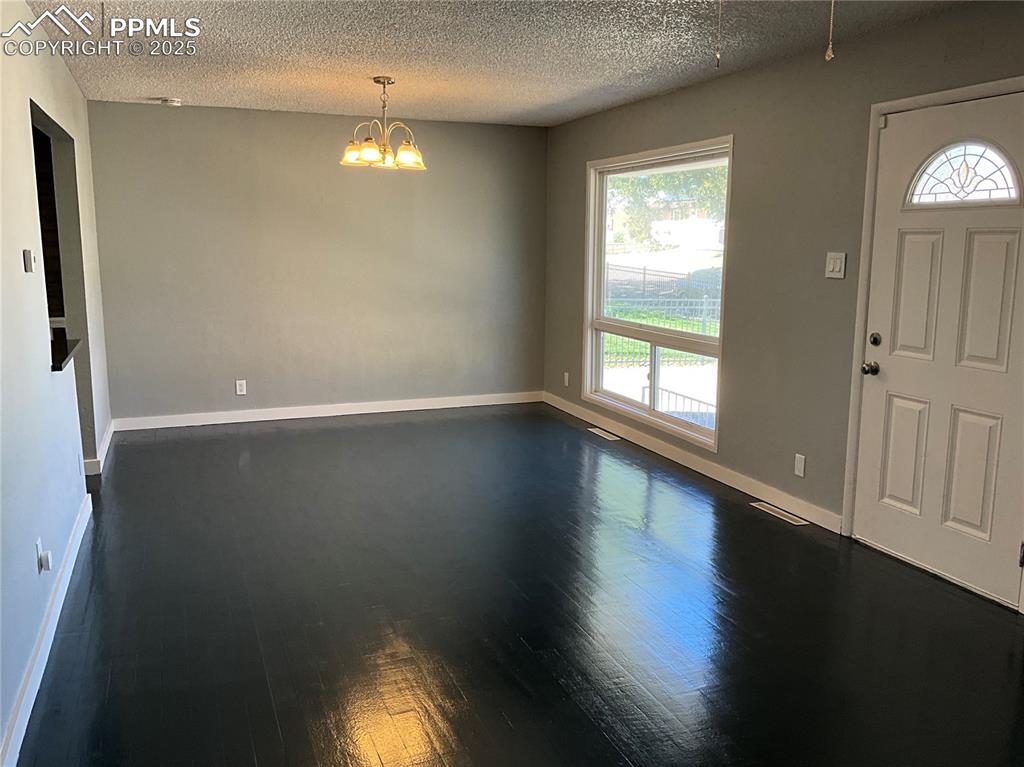 Image 12 of 43: Foyer with dark wood-style floors, a chandelier, and a textured ceiling