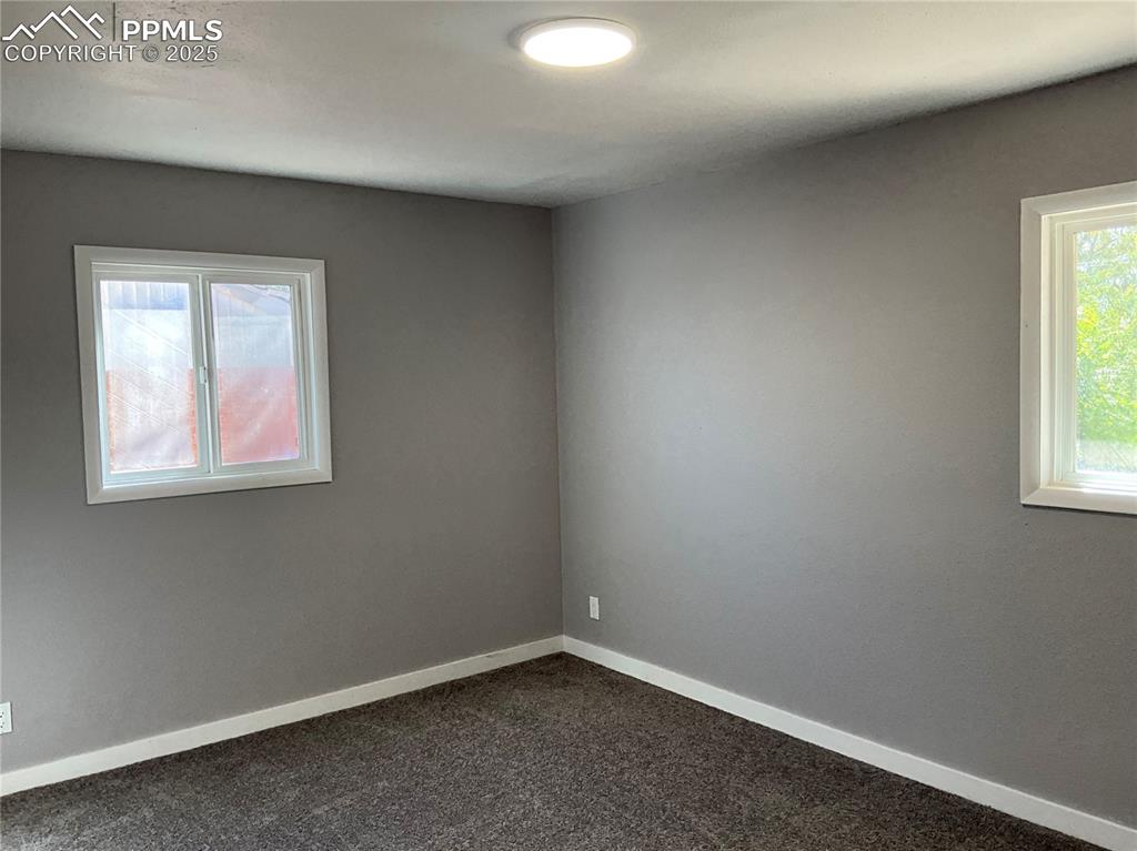 Image 14 of 43: Unfurnished room with baseboards and dark colored carpet