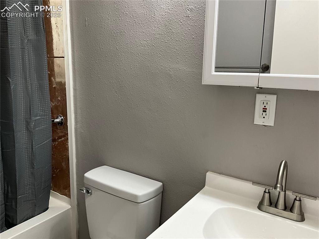 Image 17 of 41: Bathroom with a textured wall, shower / bath combo with shower curtain, and