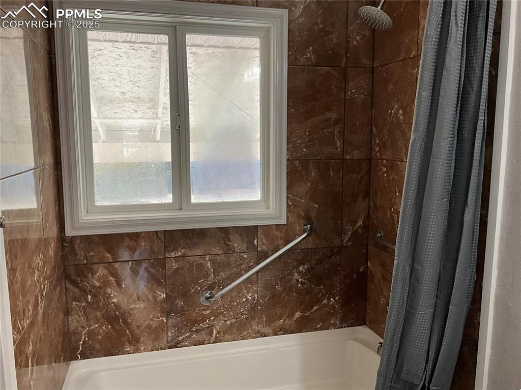Image 21 of 43: Bathroom with plenty of natural light and shower / bath combo with shower c