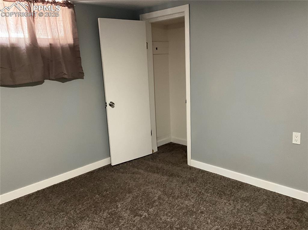 Image 31 of 43: Unfurnished bedroom with dark colored carpet and baseboards