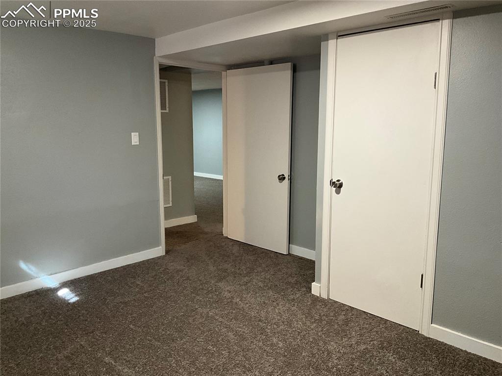 Image 33 of 43: Unfurnished bedroom with dark carpet and baseboards