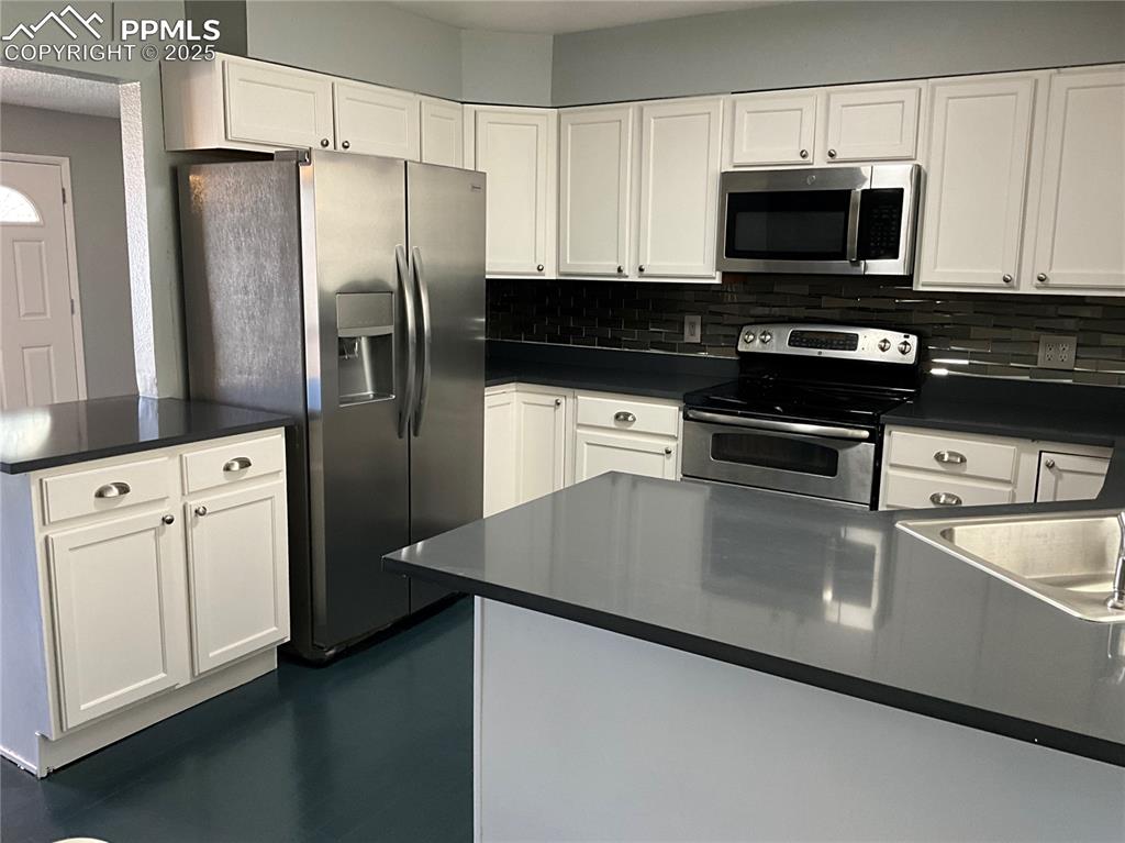 Image 5 of 43: Kitchen with appliances with stainless steel finishes, white cabinetry, dec
