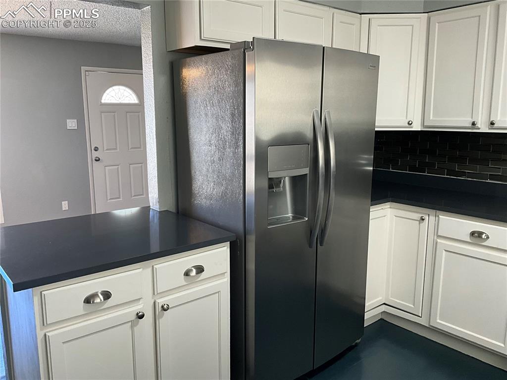 Image 6 of 43: Kitchen with stainless steel fridge with ice dispenser, white cabinetry, de
