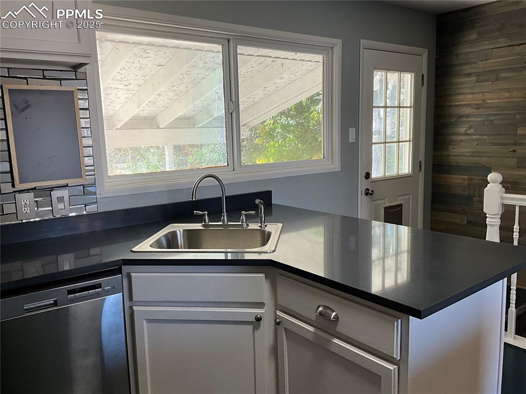 Image 8 of 43: Kitchen featuring dark countertops, gray cabinets, stainless steel dishwash