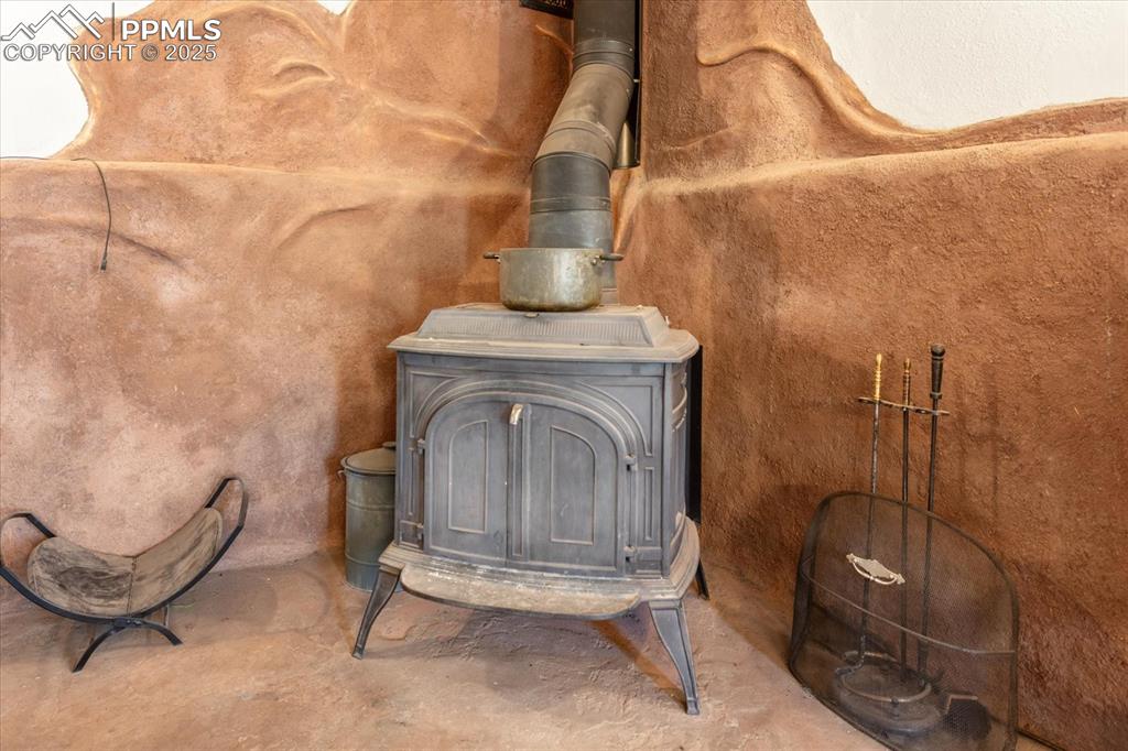 Image 10 of 45: Detailed view of a wood stove and concrete flooring