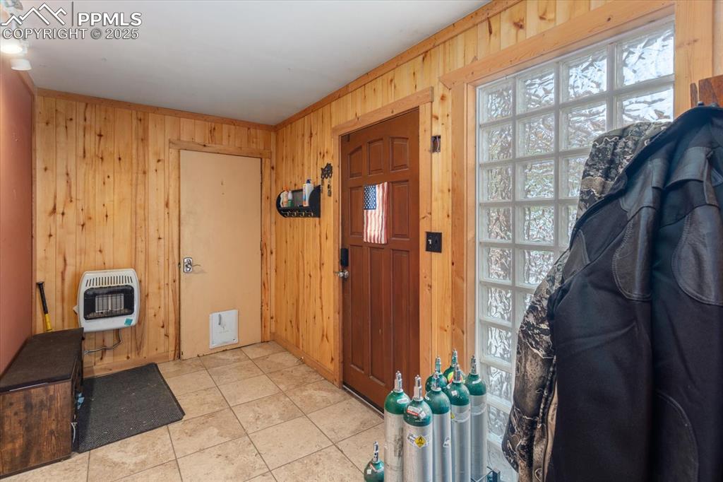 Image 15 of 45: Foyer with heating unit, wooden walls, and light tile patterned flooring