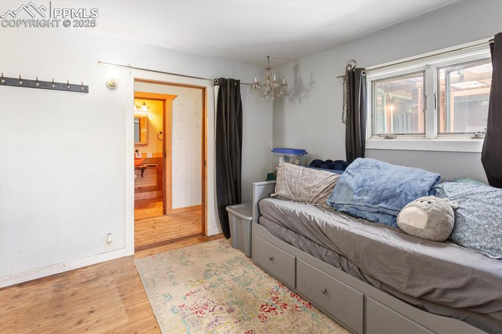 Image 17 of 45: Bedroom with wood finished floors, a chandelier, baseboards, and ensuite ba