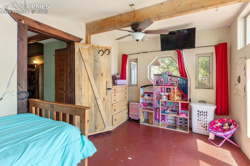 Image 25 of 45: Bedroom featuring beam ceiling, finished concrete floors, and a ceiling fan