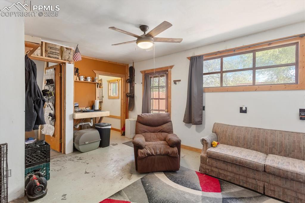 Image 35 of 45: Living room featuring unfinished concrete flooring, ceiling fan, and basebo