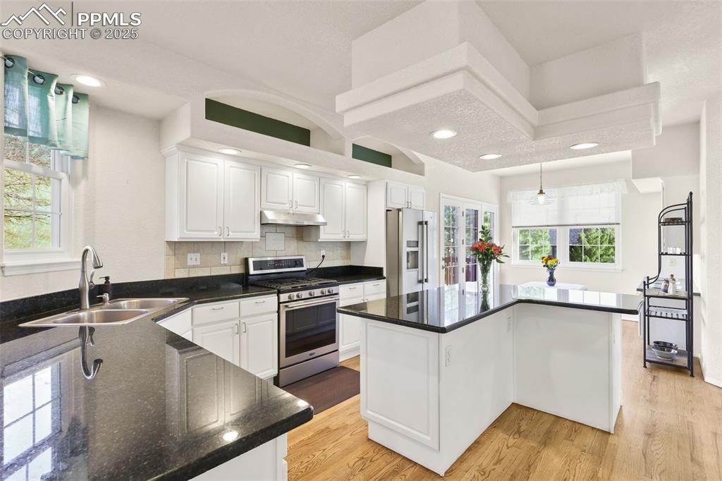 Image 10 of 49: Kitchen featuring white cabinets, stainless steel appliances, a center isla