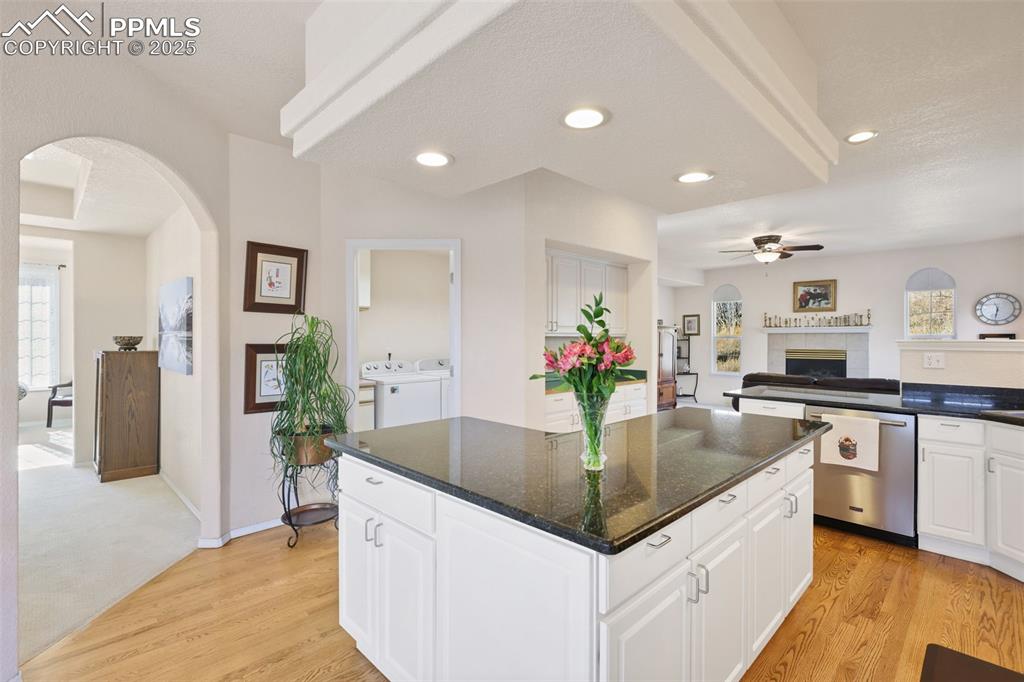Image 12 of 49: Kitchen with arched walkways, open floor plan, light wood-style flooring, c