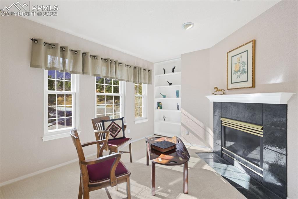 Image 18 of 49: Sitting room featuring a tiled fireplace and carpet