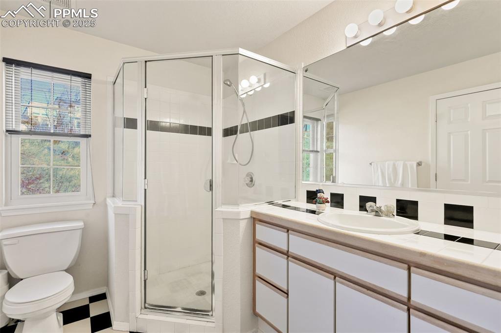 Image 24 of 49: Bathroom featuring a shower stall, vanity, healthy amount of natural light,