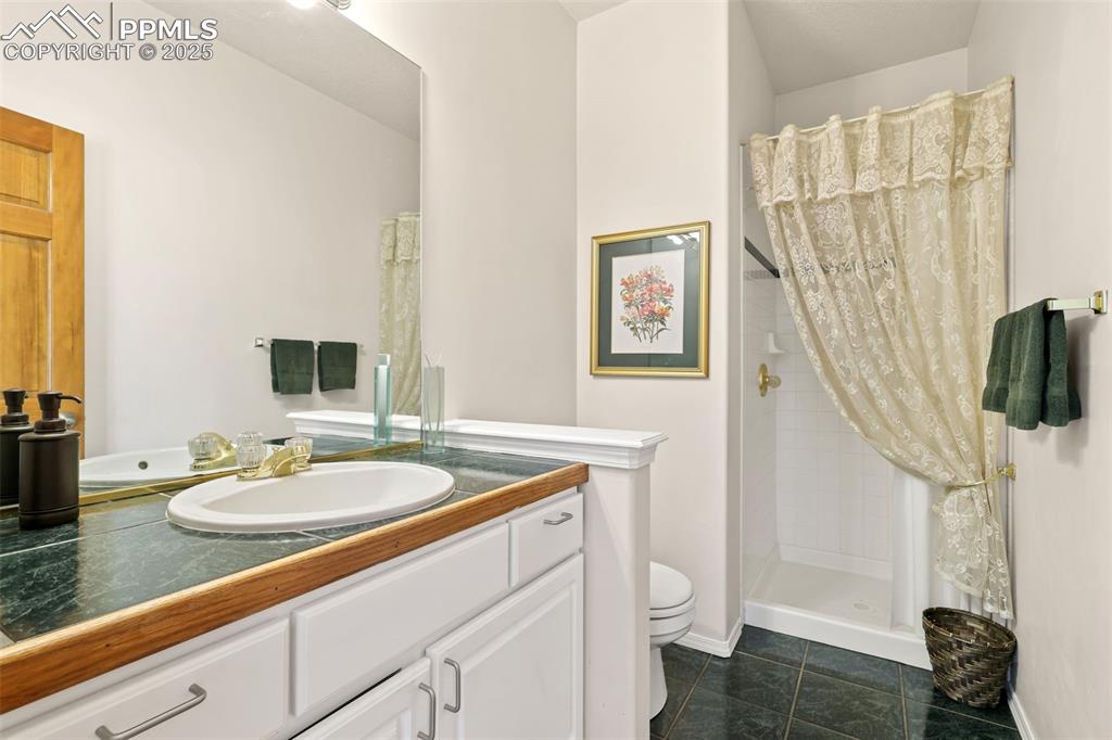 Image 30 of 49: Bathroom with a shower stall, vanity, and dark tile patterned flooring