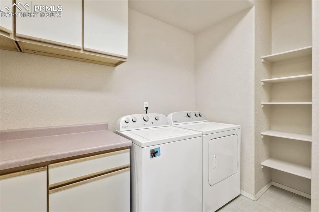 Image 32 of 49: Washroom with cabinet space and washer and clothes dryer