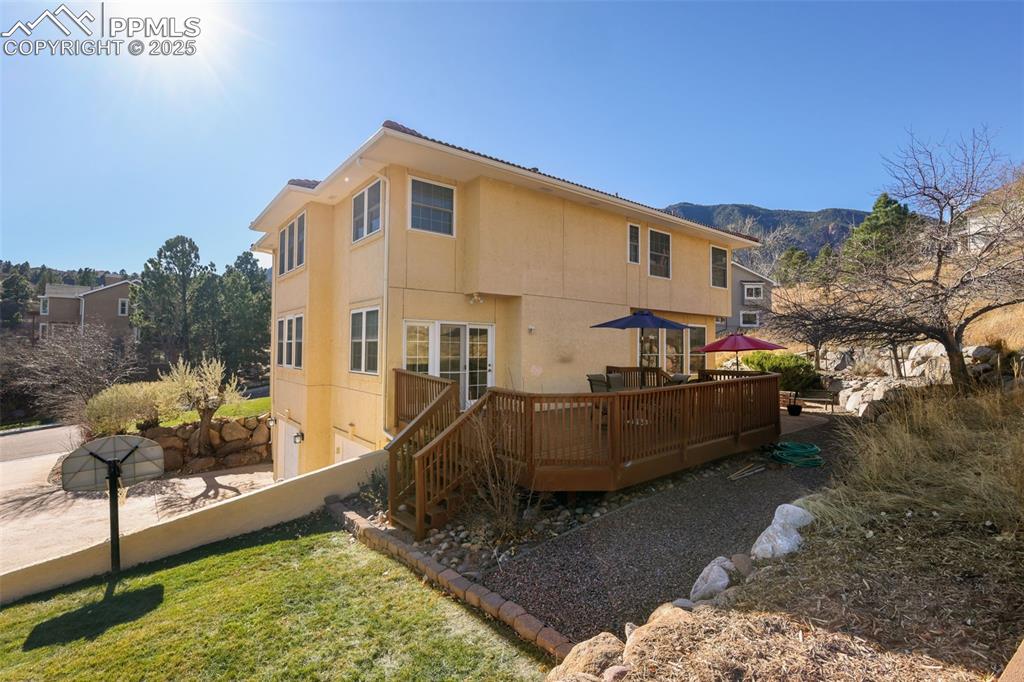 Image 39 of 49: Rear view of house featuring stucco siding, a deck with mountain view, and 