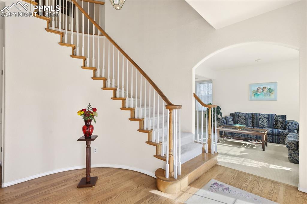 Image 6 of 49: Stairway featuring wood finished floors, arched walkways, and a towering ce