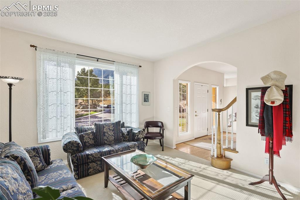 Image 8 of 49: Carpeted living room featuring arched walkways and stairway