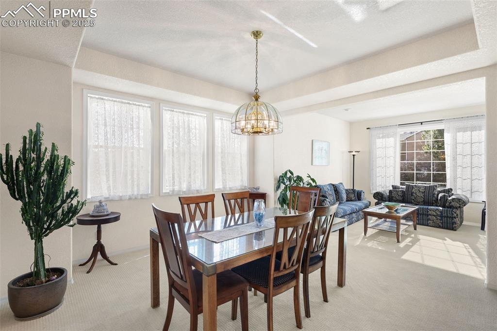 Image 9 of 49: Dining space with light carpet and a chandelier