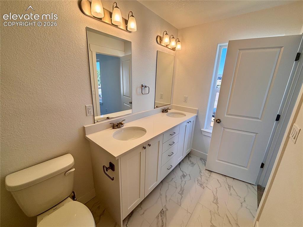 Image 19 of 23: Dual vanity with integrated sinks, white cabinetry, and a light-colored cou