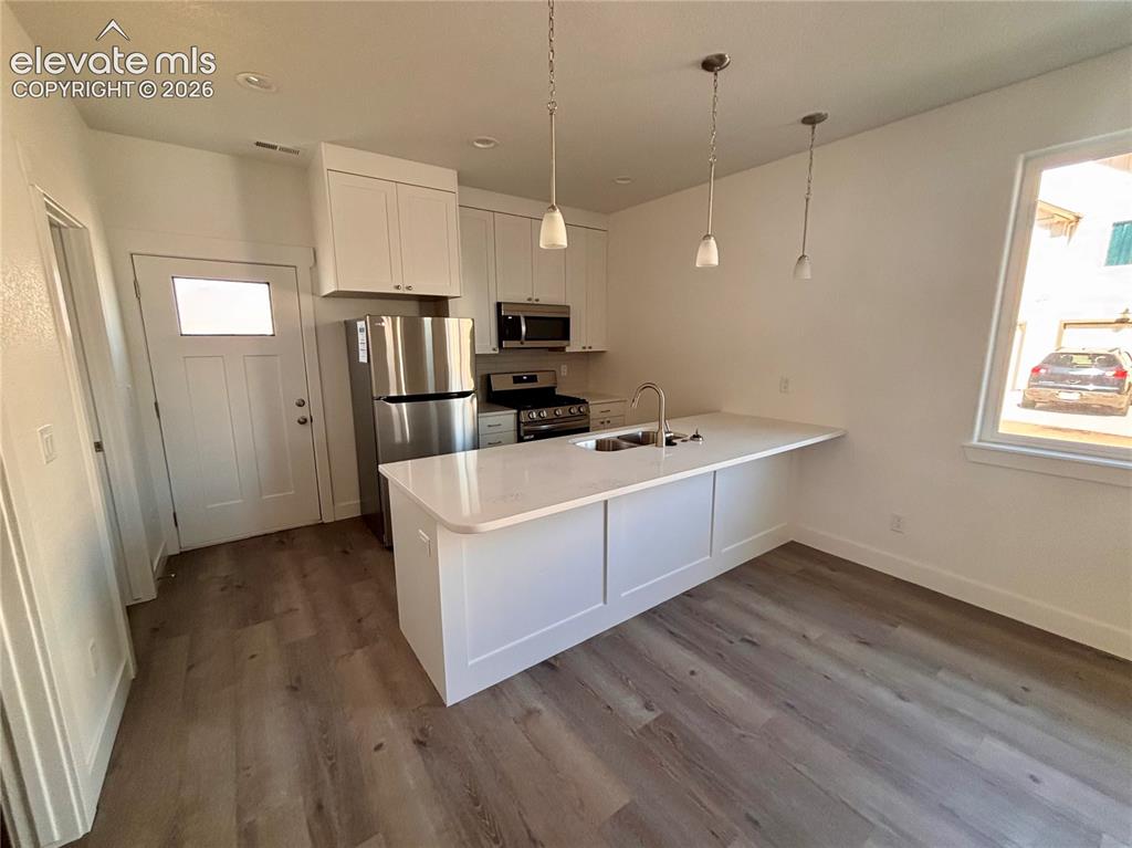 Image 7 of 23: Kitchen featuring white cabinetry, stainless steel appliances, a white isla