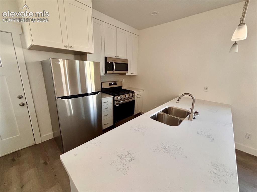 Image 8 of 23: Kitchen featuring white cabinetry, stainless steel appliances, a double bas