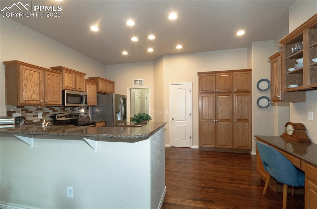 Image 12 of 43: Many oak cabinets with crown molding, quartz countertops and SS appliances.