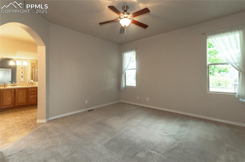 Image 20 of 43: Convenient main level primary bedroom is spacious with neutral carpet.