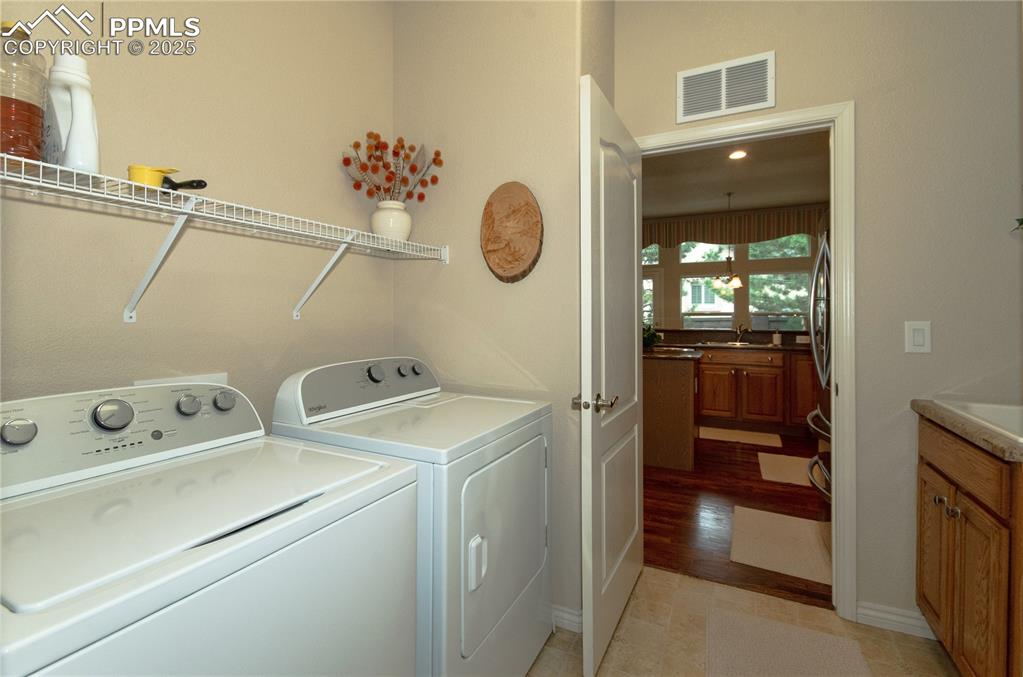 Image 25 of 43: Main floor laundry has storage closet, cabinet with sink & washer/dryer.