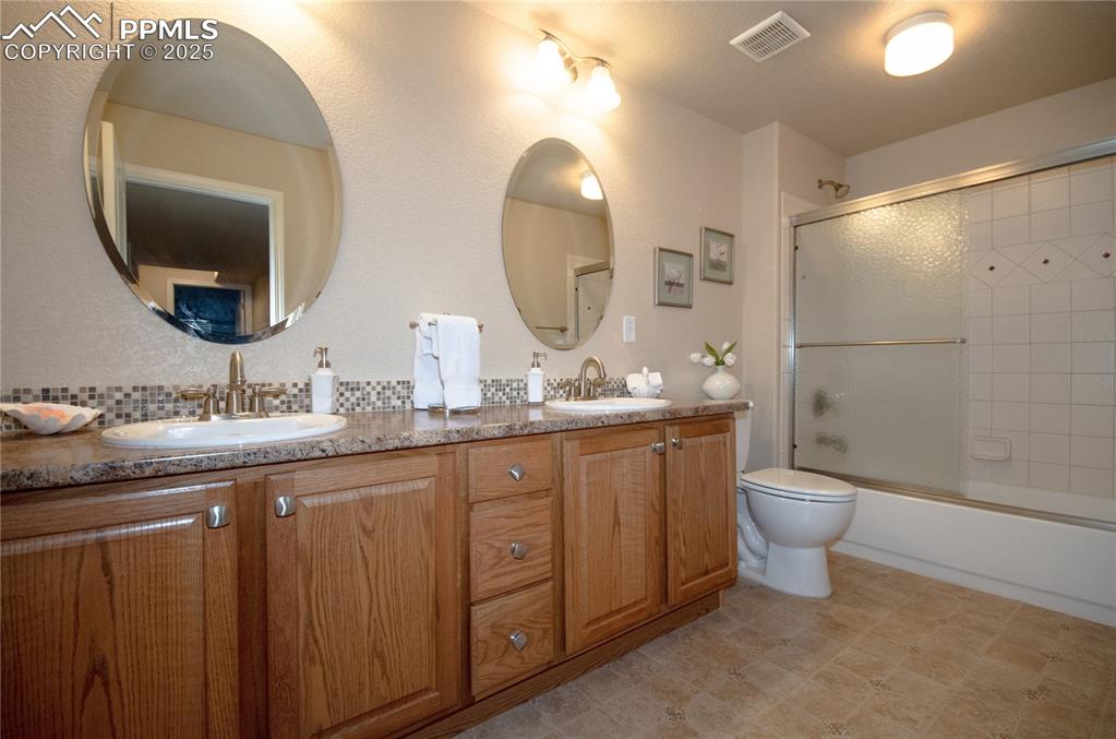 Image 34 of 43: Spacious lower level full bath with duel sinks, oak cabinets, tiled tub/sho