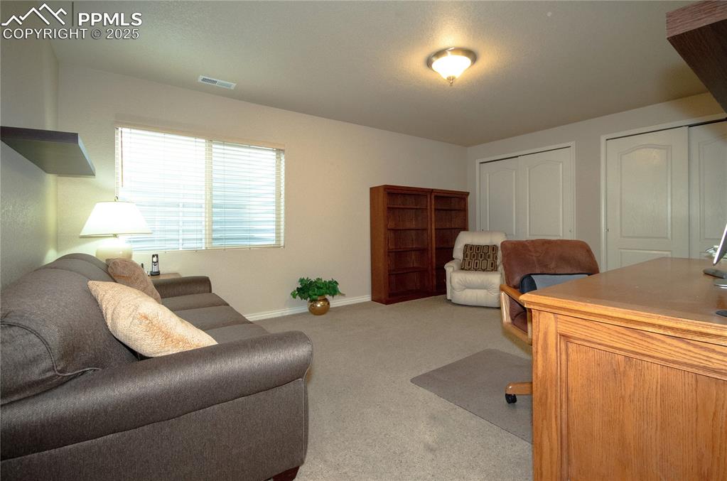Image 37 of 43: Lower level bedroom 2, currently used as an office, with large dual closets