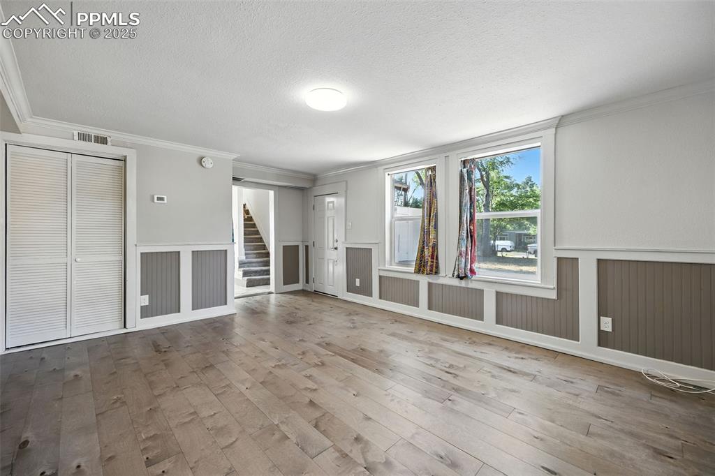 Image 10 of 25: Unfurnished living room featuring ornamental molding, light wood-style floo