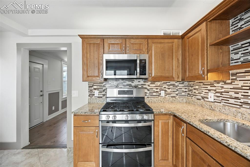 Image 15 of 25: Kitchen with light stone countertops, appliances with stainless steel finis
