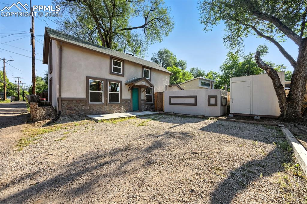 Image 2 of 25: View of front facade featuring stucco siding, stone siding, and a storage s