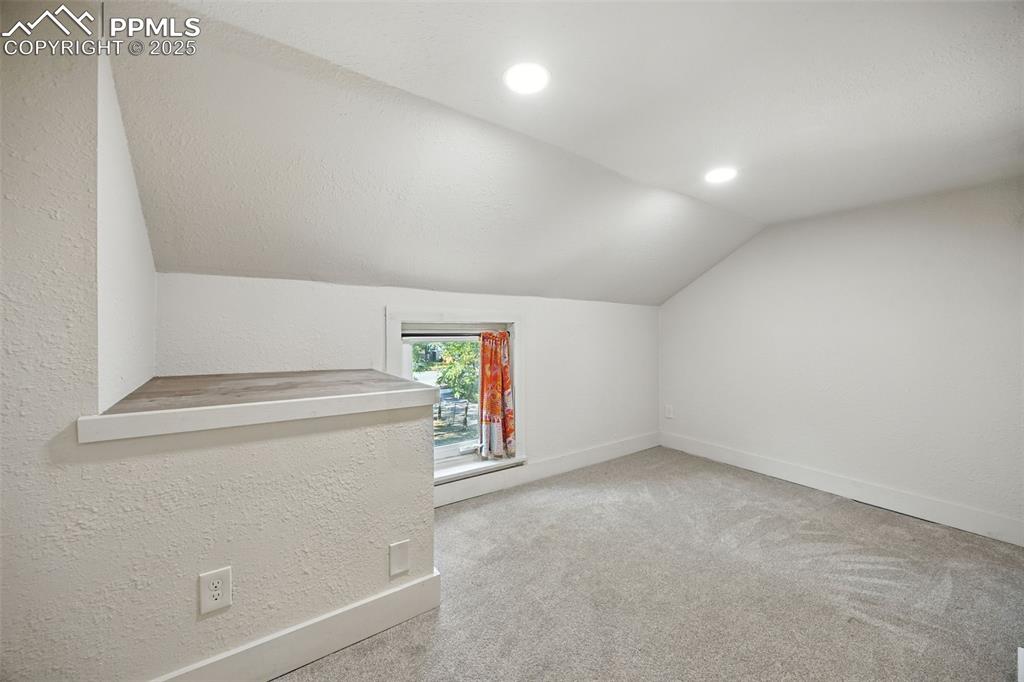 Image 20 of 25: Bonus room featuring vaulted ceiling, light colored carpet, a textured wall