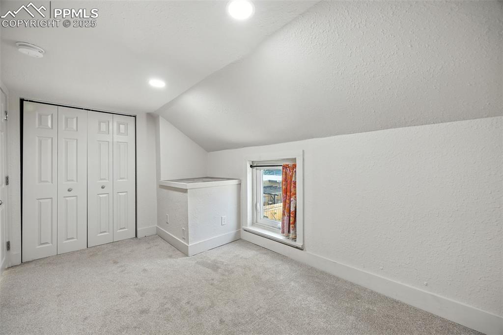 Image 22 of 25: Bonus room with carpet, lofted ceiling, a textured ceiling, a textured wall