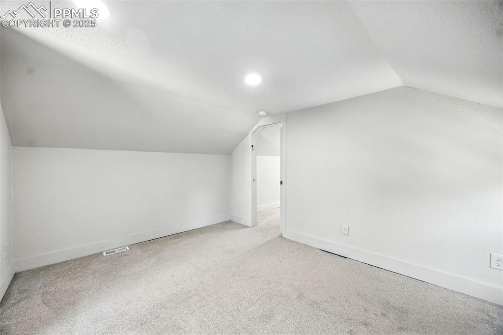 Image 25 of 25: Additional living space with lofted ceiling and carpet