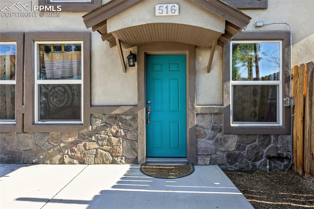 Image 3 of 25: Property entrance with stone siding and stucco siding