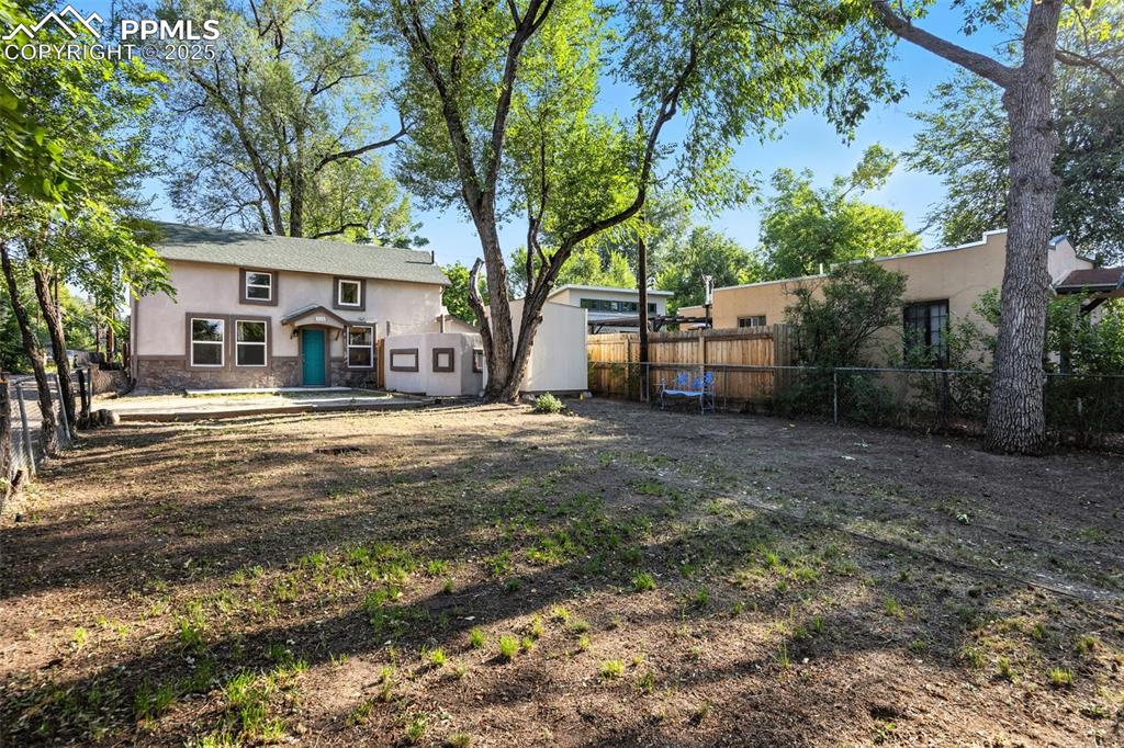 Image 4 of 25: Back of house with a fenced backyard, stucco siding, a patio area, and ston