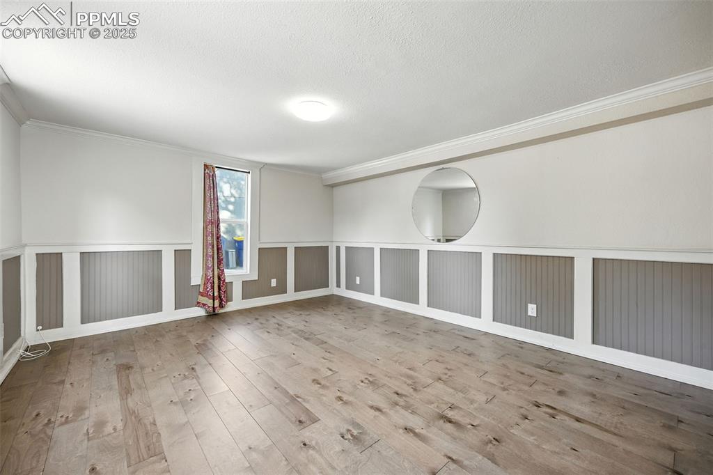 Image 8 of 25: Spare room featuring ornamental molding, light wood-style floors, and a tex