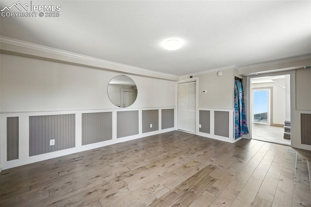 Image 9 of 25: Unfurnished room with ornamental molding, wood-type flooring, and a texture