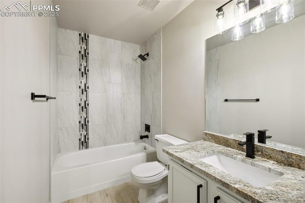 Image 16 of 29: Bathroom featuring toilet, vanity, shower / tub combination, and wood finis